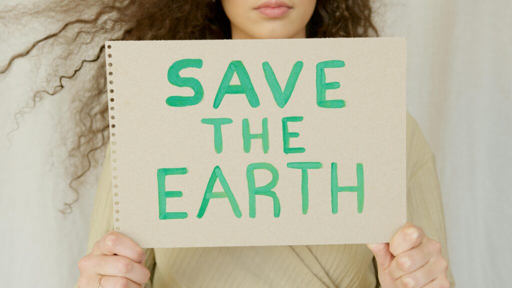 Close-up of a woman holding a save the earth sign promoting environmental awareness.
